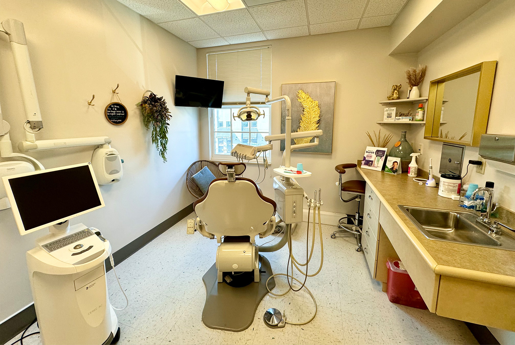 The image depicts a dental office interior with various equipment and furnishings, including a dentist s chair, examination table, sink, monitor, and other dental tools.