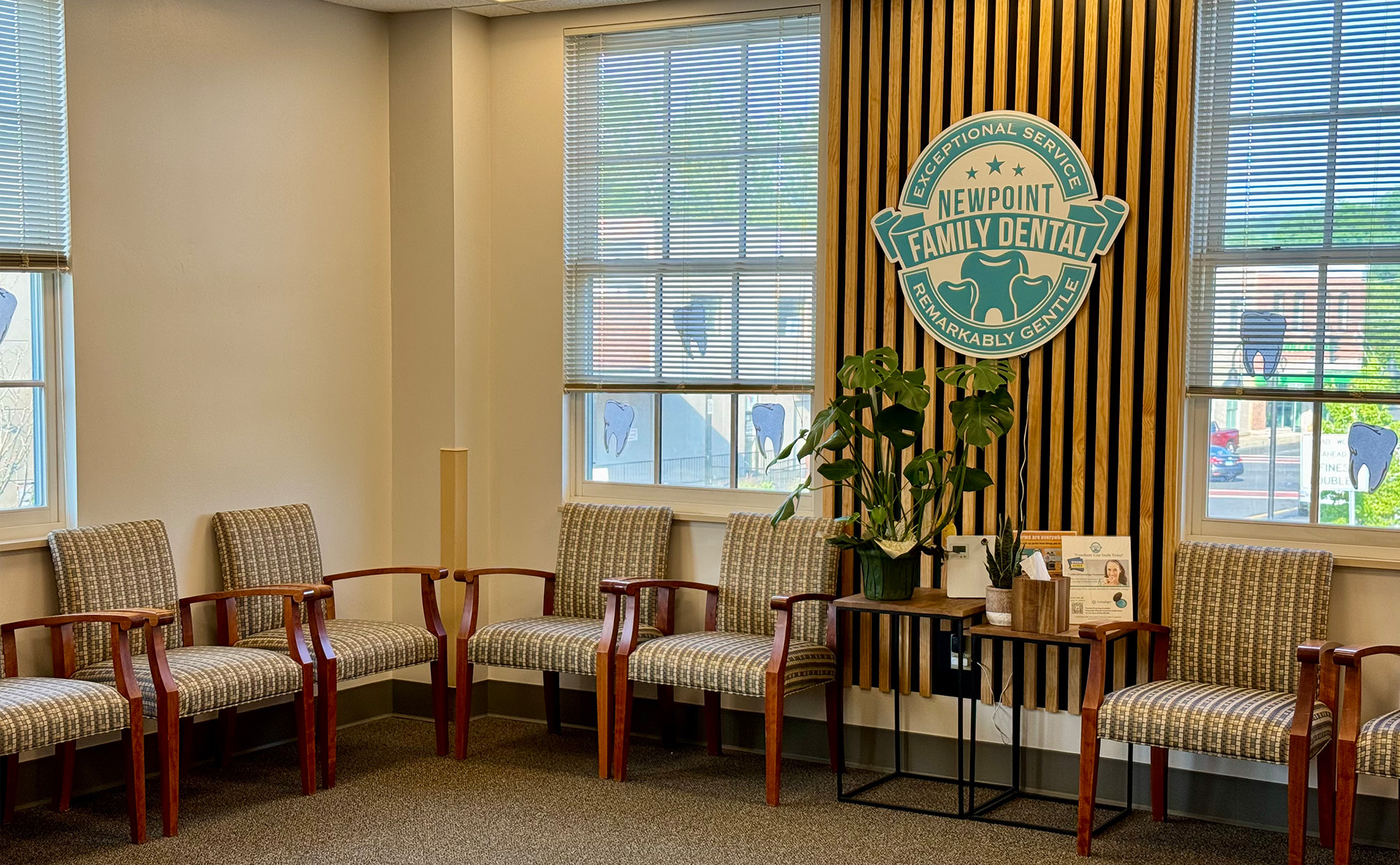 The image shows an interior space with a sign that reads  Naperville Downtown  and features furniture including chairs and a couch, along with decorative elements such as framed pictures and a potted plant.