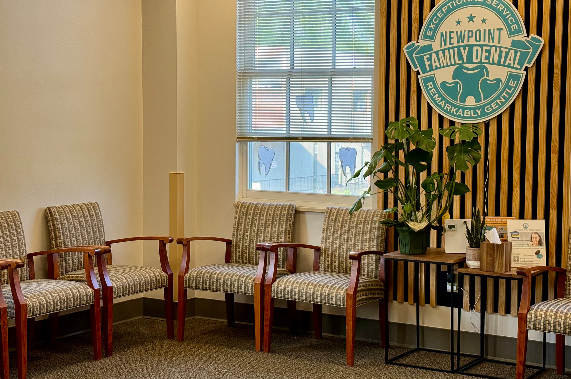 The image shows an interior space with a waiting area, featuring chairs and a sign that reads  Family Dental.  There is also a wall-mounted logo for  Newpoint Family Dental  and a window with blinds partially drawn.