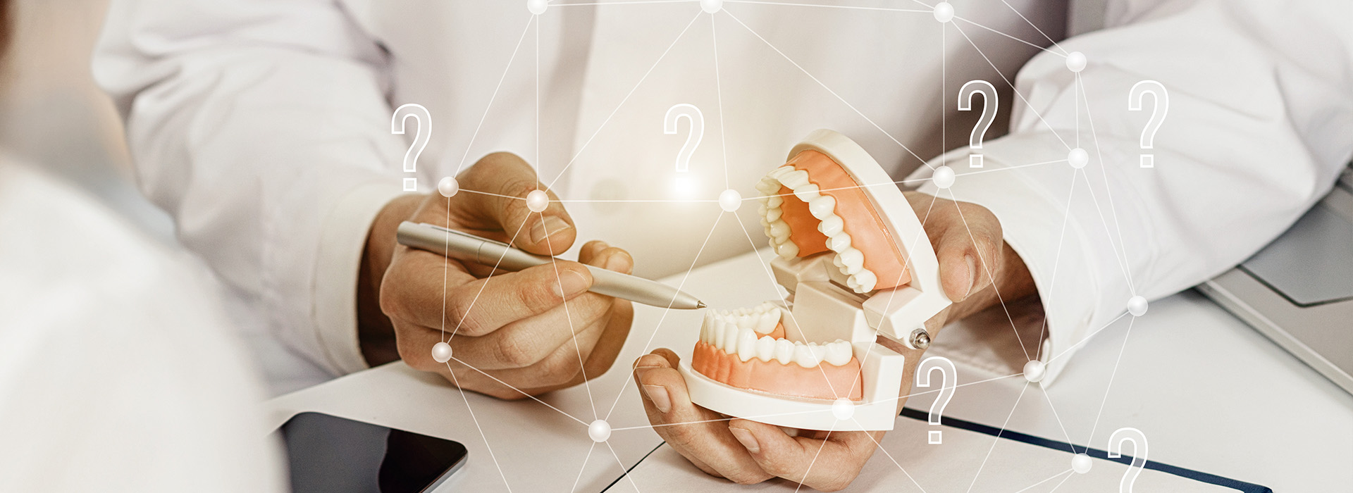 A dental professional holding a model of a tooth in front of a digital representation of the human mouth, with a focus on oral health and dental care.