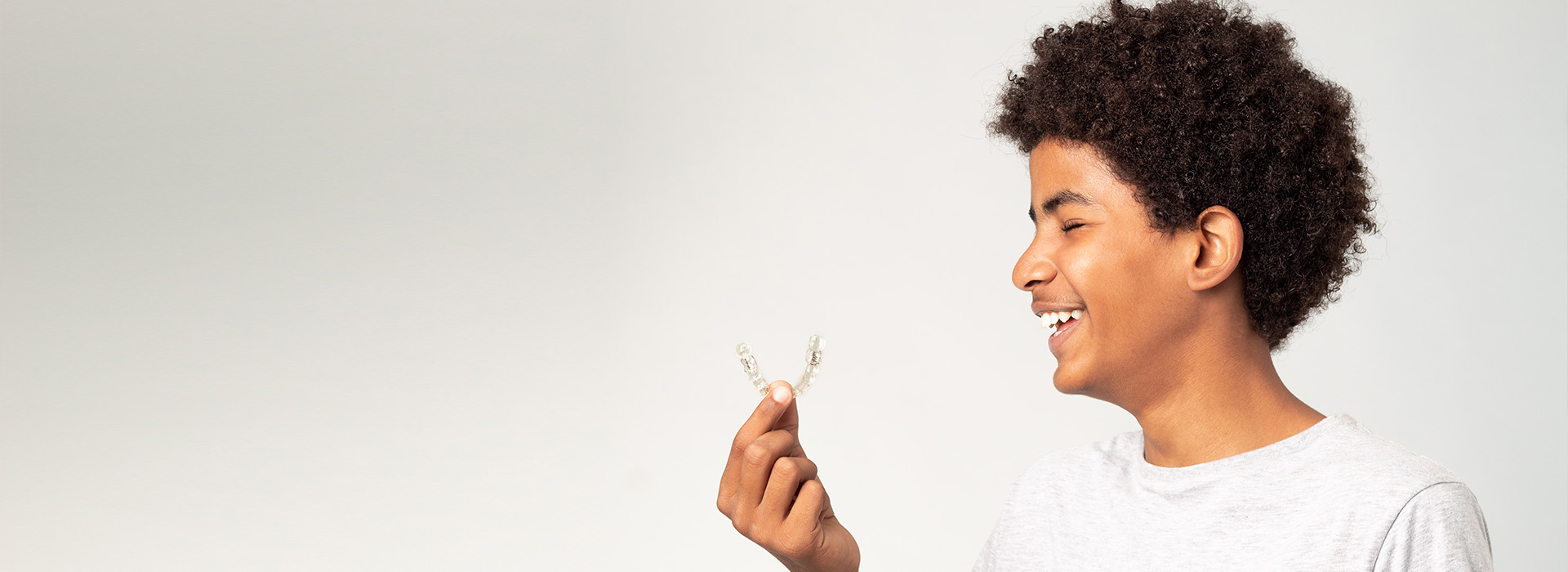 The image shows a person holding a flower with a joyful expression, set against a plain background.