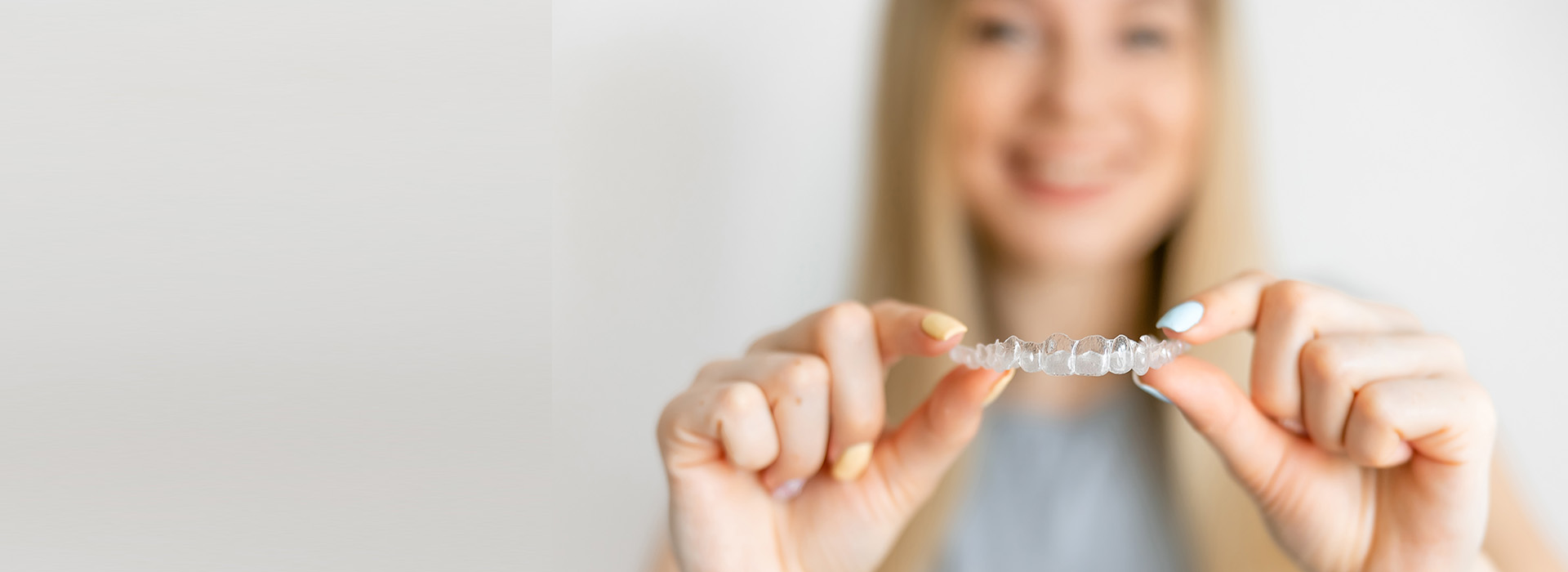 A smiling person holding a small, clear object with both hands.