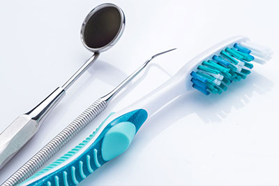 This image features a collection of dental tools, including a toothbrush with blue bristles and a pair of scissors, set against a white background.