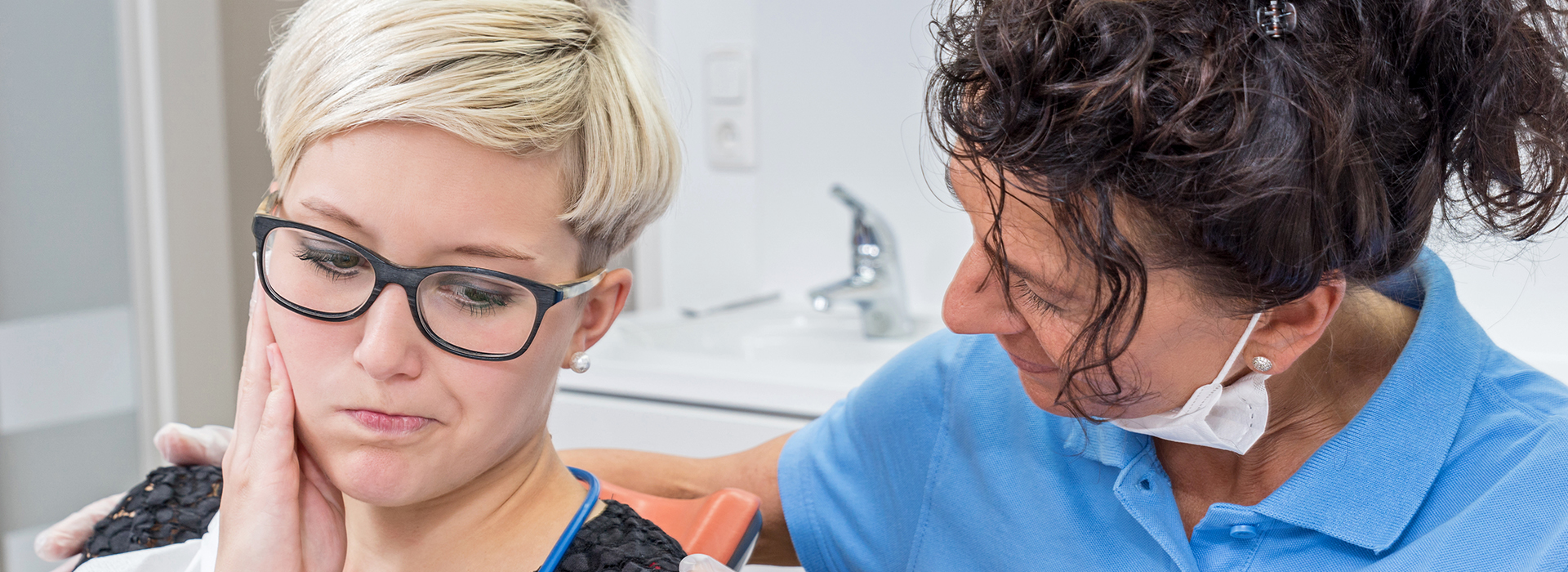 The image shows a woman with a shaved head being attended to by a professional in what appears to be a dental or beauty setting.