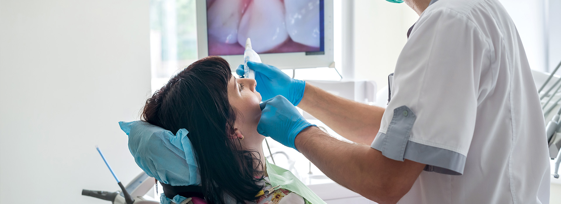 A dental professional is performing a procedure on a patient s teeth, with the dentist wearing protective gloves and a mask.