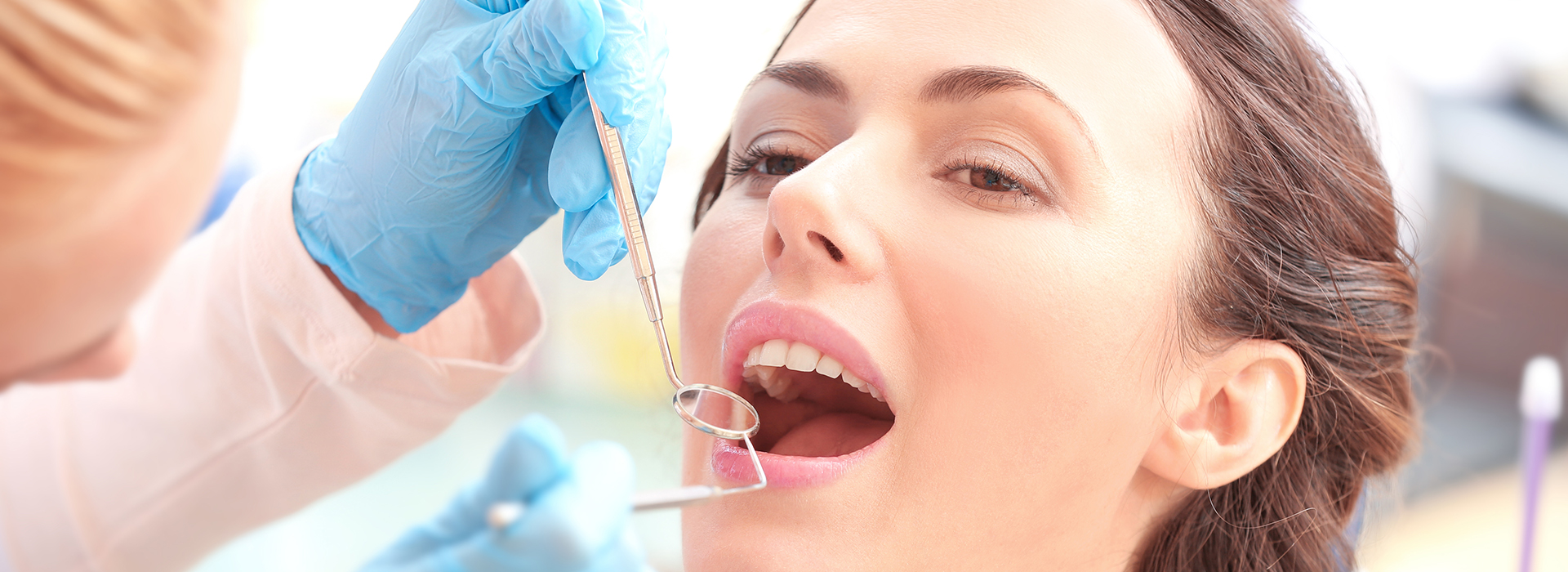 A dental hygienist performing a teeth cleaning procedure on a patient, with the focus on the dental tools in use.