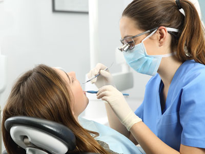 A dental hygienist performing a teeth cleaning procedure on a patient in a dental office setting.