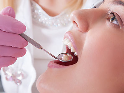 This is a photograph of a dental professional performing an oral procedure on a patient, with the focus on the dentist s hand holding a dental tool near the patient s mouth.