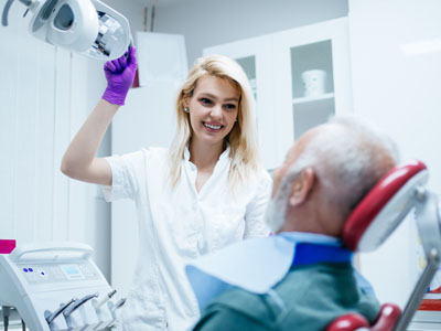 A dental professional is assisting a patient in a dental office, with the patient seated comfortably and receiving care.