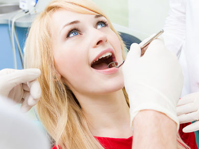 The image features a woman in a dental chair, receiving dental care from a dentist.