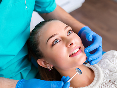 A dental professional performing a procedure on a patient in a clinical setting.