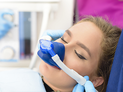 The image shows a person receiving medical attention, with a healthcare professional using a medical device on their face while the individual appears to be lying down and possibly undergoing a procedure or treatment.